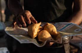 A vendor holds up freshly made samosas, a fried street food in Delhi.